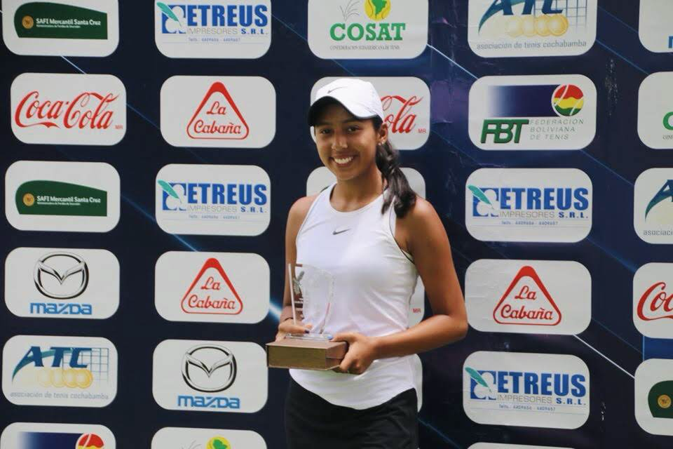 Valeria holding a trophy in a white outfit