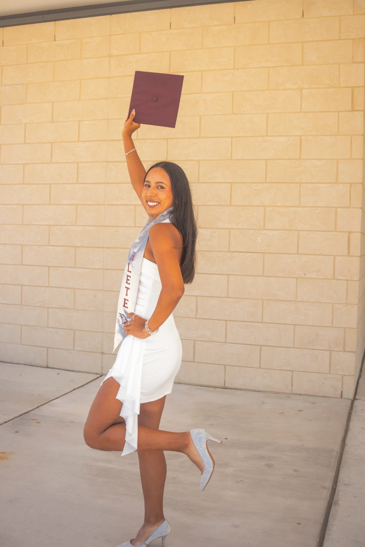 Valeria celebrating her degree with her diploma raised above her head